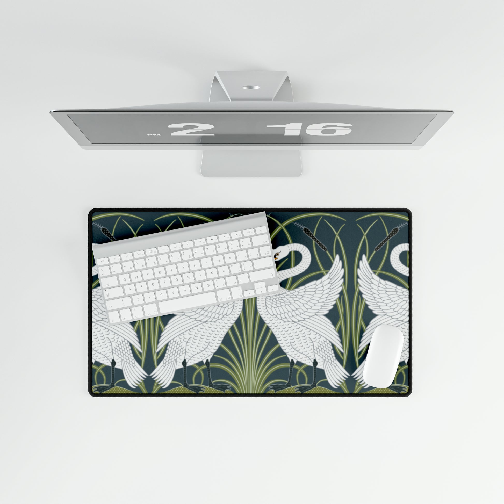 A rectangular desk mat with a floral and swan William Morris & Co pattern design, featuring a white background and swans, placed under a white mouse pad with a keyboard on top.