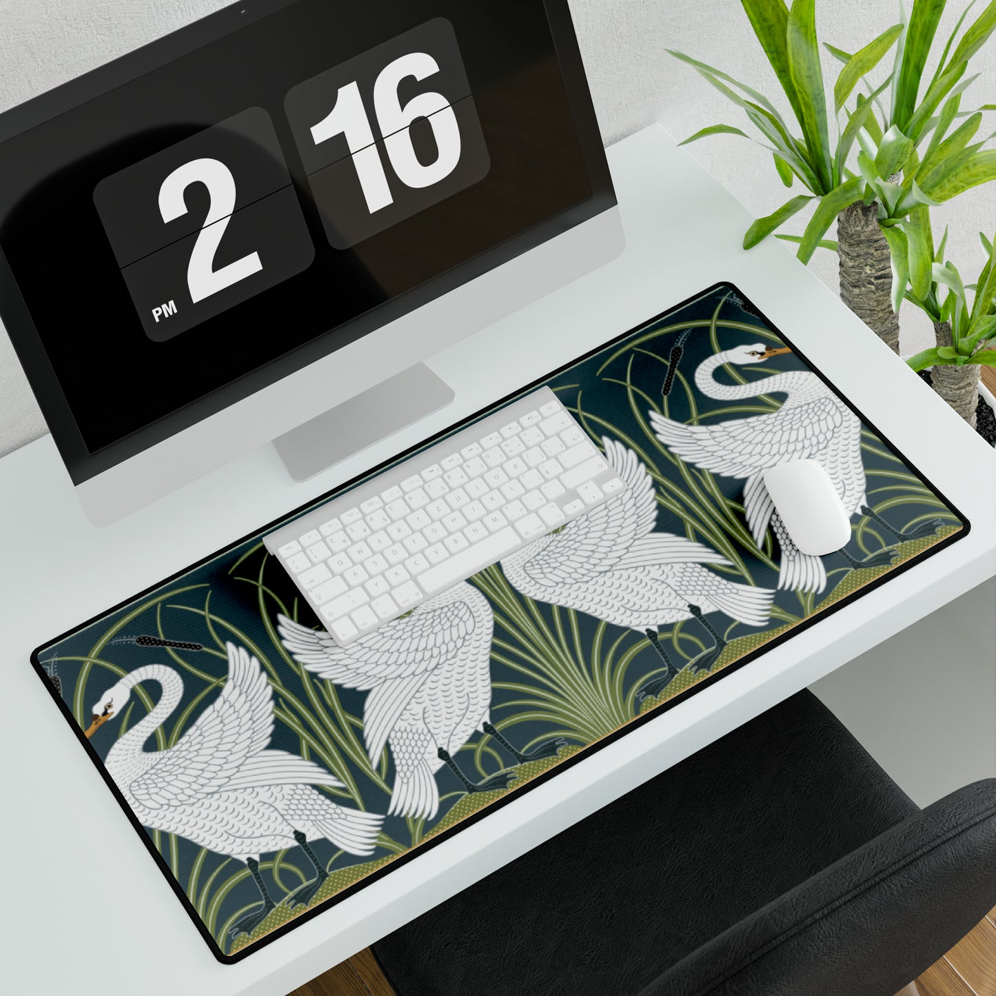 A rectangular desk mat with a floral and swan William Morris & Co pattern design, featuring a white background and swans, placed under a white mouse pad with a keyboard on top.