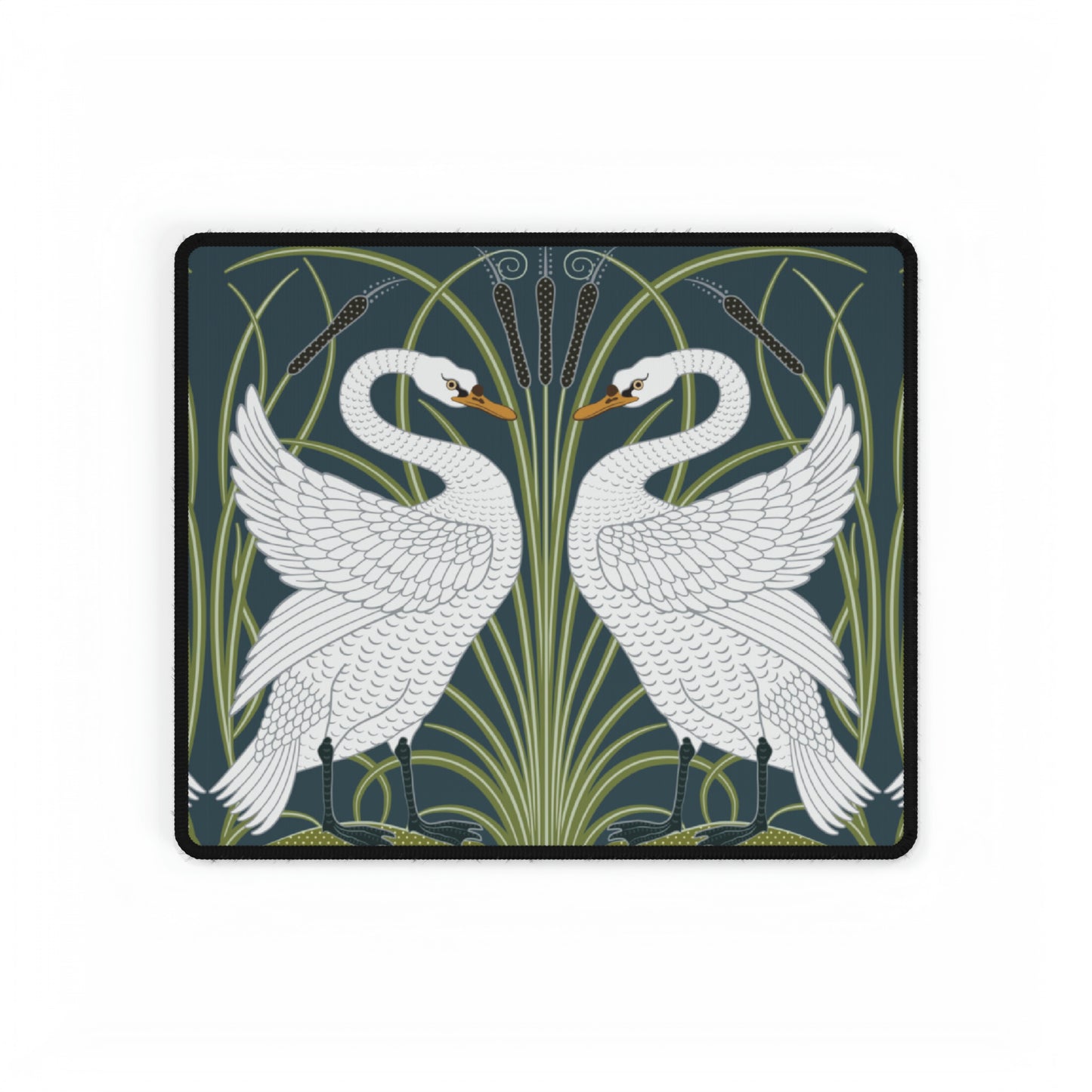 A rectangular desk mat with a floral and swan William Morris & Co pattern design, featuring a white background and swans, placed under a white mouse pad with a keyboard on top.