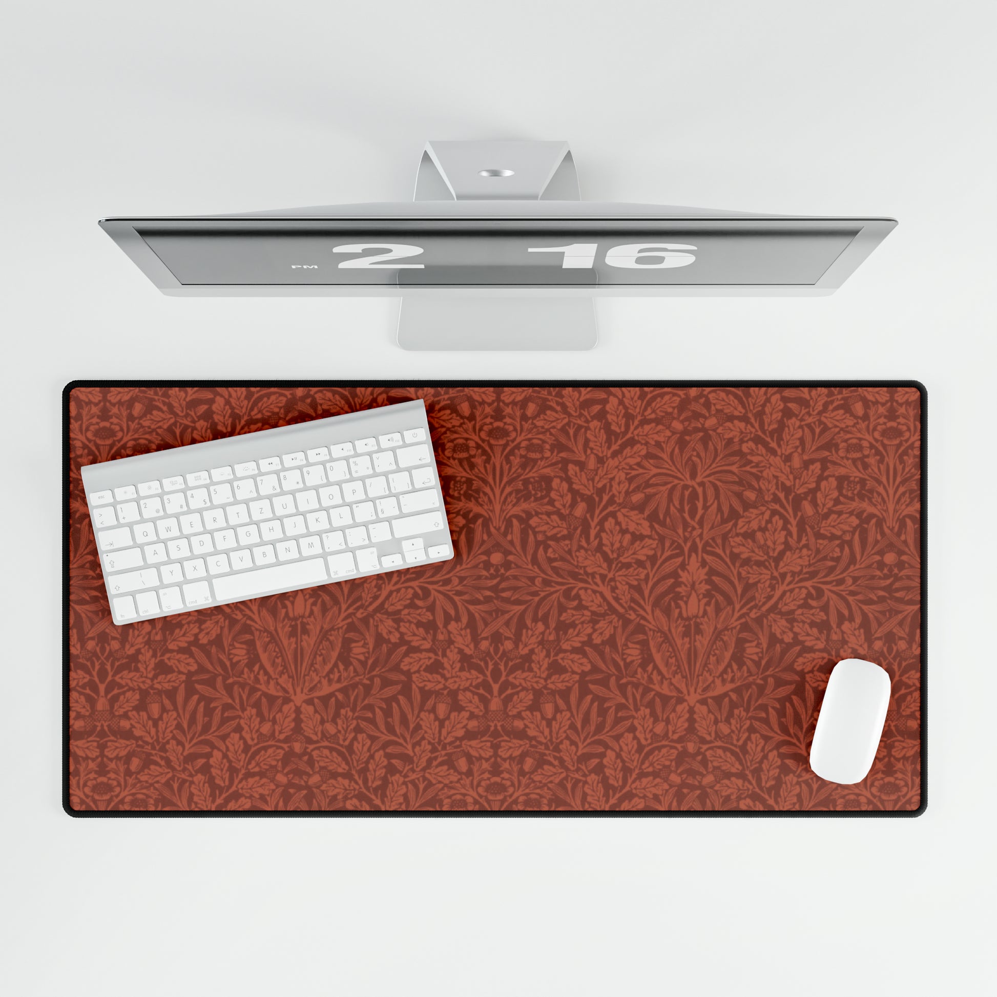 A large desk mat with a floral pattern in brown tones, displayed on a desk with a keyboard and mouse, with a monitor above it showing the time.
