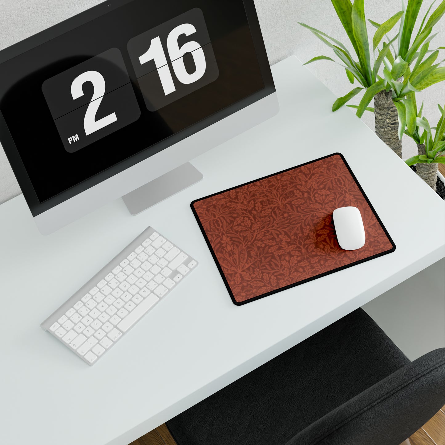 A large desk mat with a floral pattern in brown tones, displayed on a desk with a keyboard and mouse, with a monitor above it showing the time.