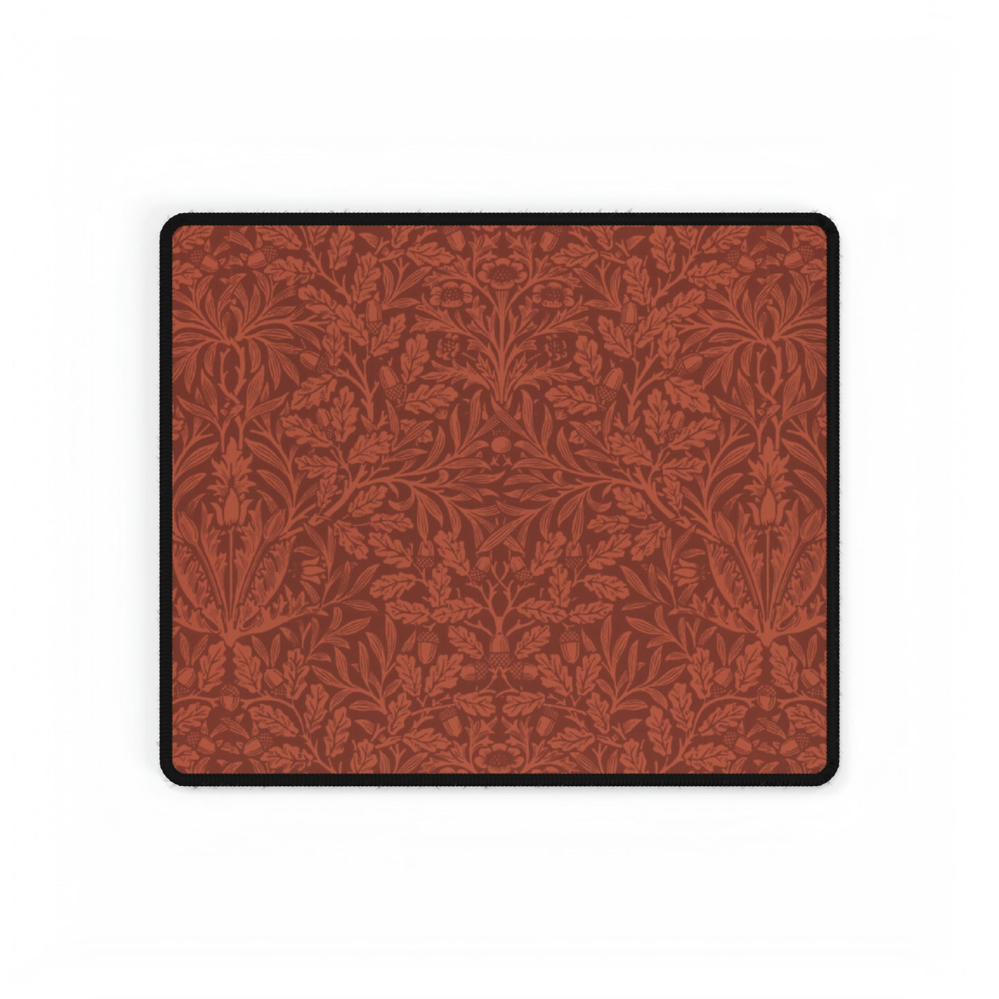 A large desk mat with a floral pattern in brown tones, displayed on a desk with a keyboard and mouse, with a monitor above it showing the time.