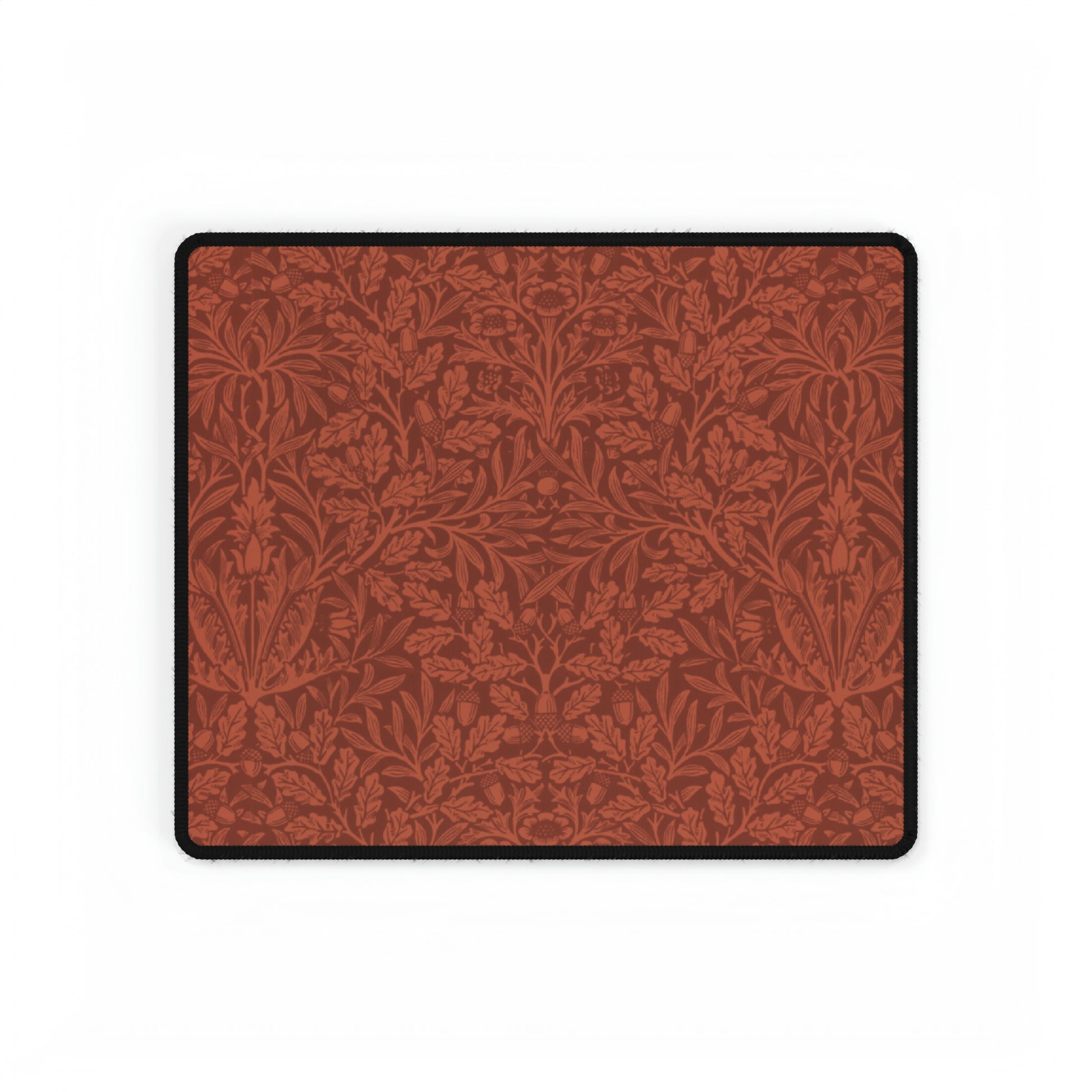 A large desk mat with a floral pattern in brown tones, displayed on a desk with a keyboard and mouse, with a monitor above it showing the time.