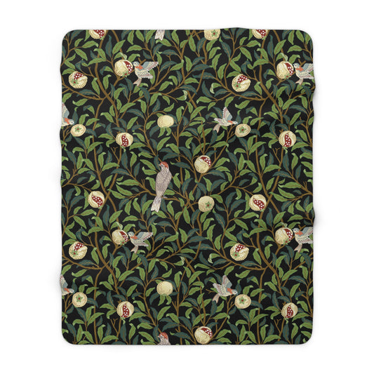 A Sherpa fleece blanket with a floral William Morris & Co pattern featuring birds and pomegranates, predominantly in green tones.