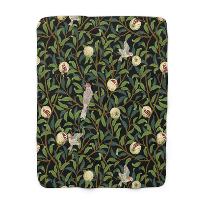 A Sherpa fleece blanket with a floral William Morris & Co pattern featuring birds and pomegranates, predominantly in green tones.
