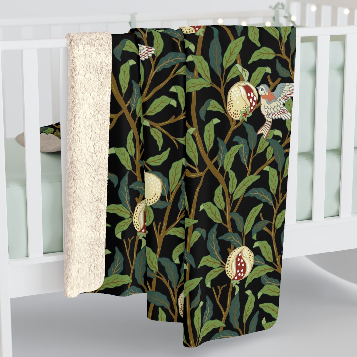 A Sherpa fleece blanket with a floral William Morris & Co pattern featuring birds and pomegranates, predominantly in green tones.