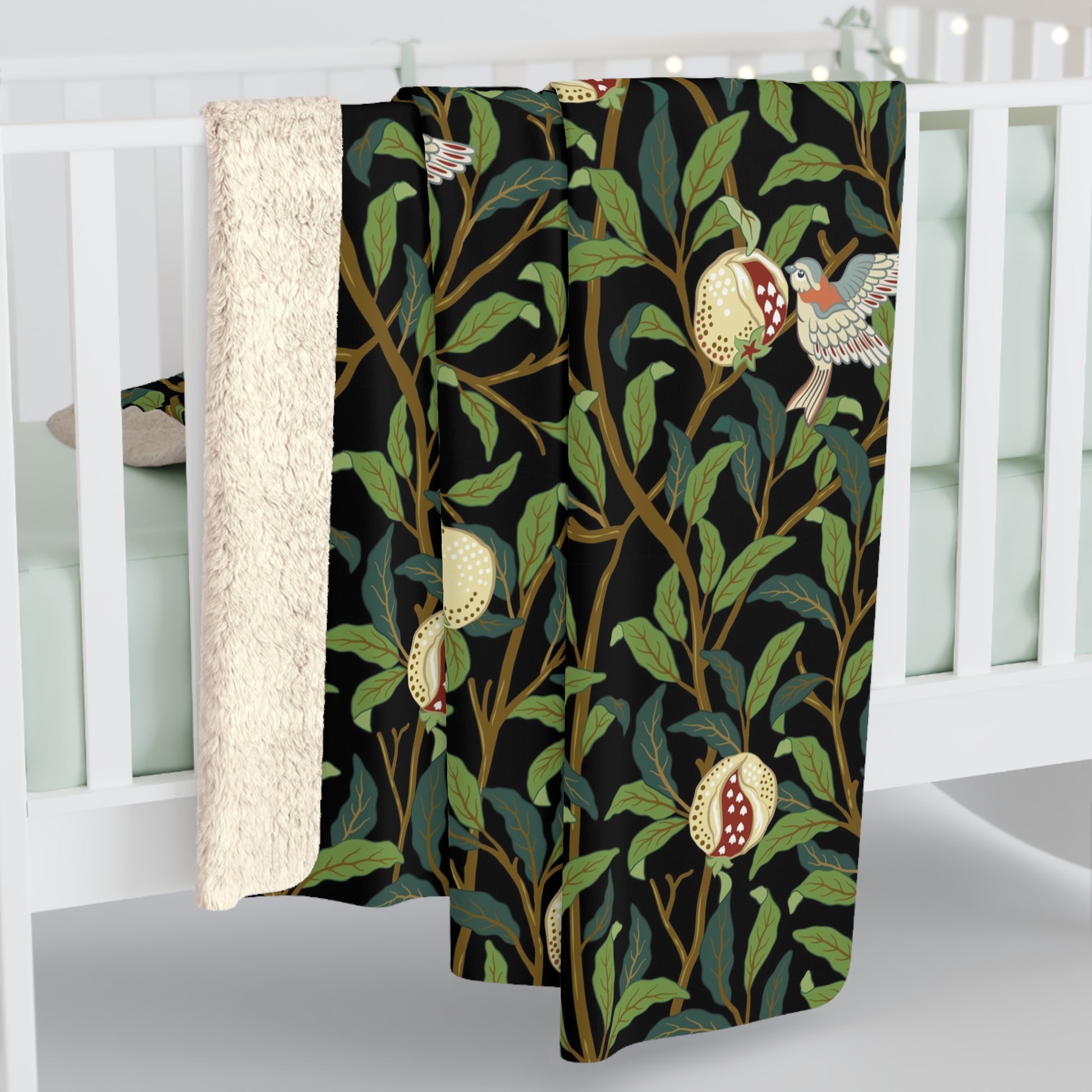 A Sherpa fleece blanket with a floral William Morris & Co pattern featuring birds and pomegranates, predominantly in green tones.