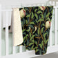 A Sherpa fleece blanket with a floral William Morris & Co pattern featuring birds and pomegranates, predominantly in green tones.