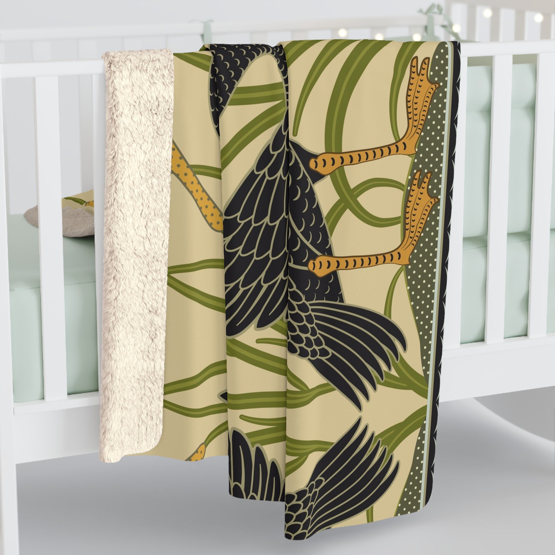 A Sherpa fleece blanket with a pattern inspired by William Morris, featuring black swans and green foliage on a beige background.