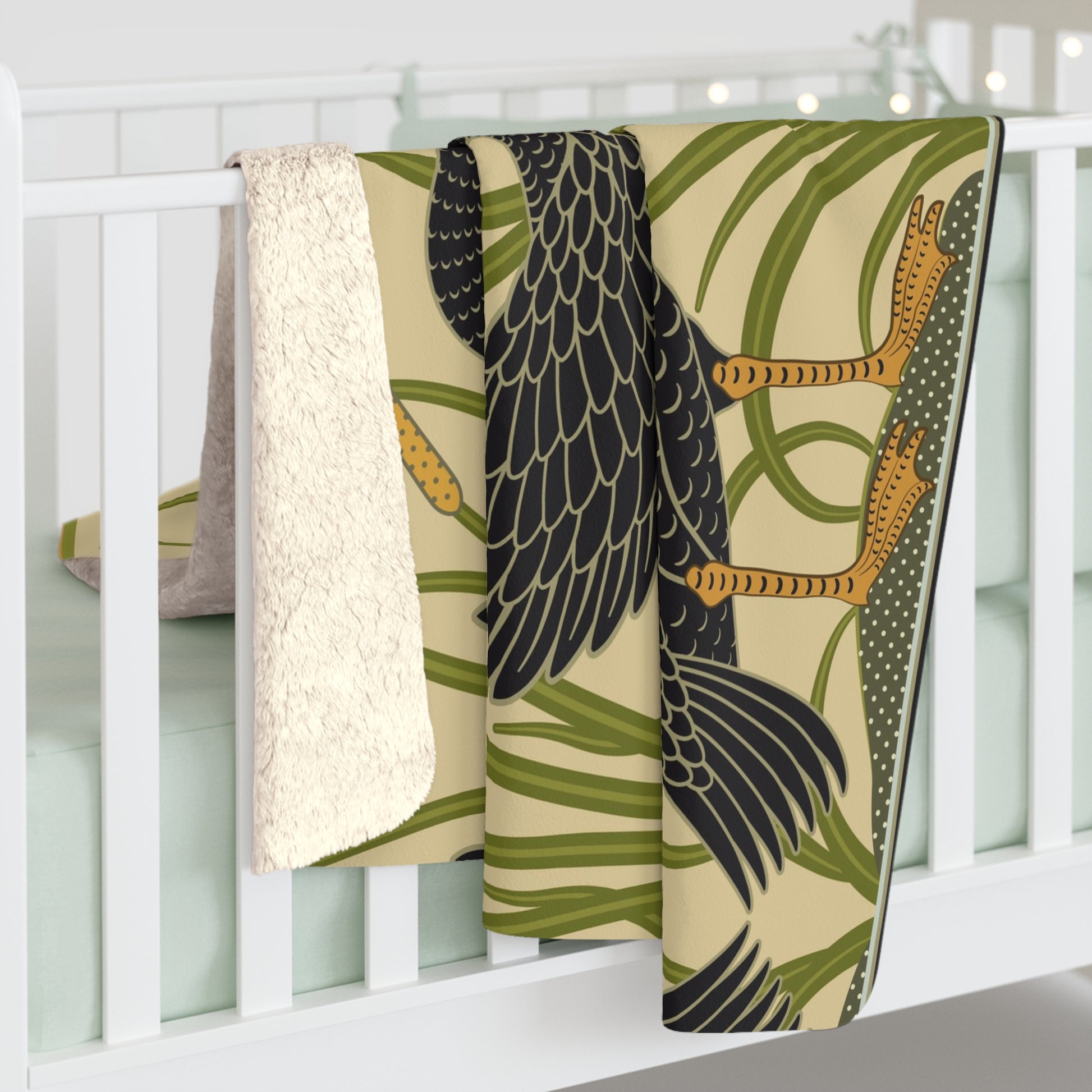 A Sherpa fleece blanket with a pattern inspired by William Morris, featuring black swans and green foliage on a beige background.