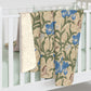 A Sherpa fleece blanket with a floral William Morris & Co pattern in blue and green on a beige background.