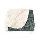 A Sherpa fleece blanket with an intricate floral and tree design, primarily in green and red tones, reflecting a natural and rustic theme.