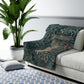 A Sherpa fleece blanket with an intricate floral and tree design, primarily in green and red tones, reflecting a natural and rustic theme.