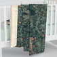 A Sherpa fleece blanket with an embossed design featuring rabbits, foxes, and green foliage on a green background.