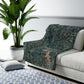 A Sherpa fleece blanket with an embossed design featuring rabbits, foxes, and green foliage on a green background.