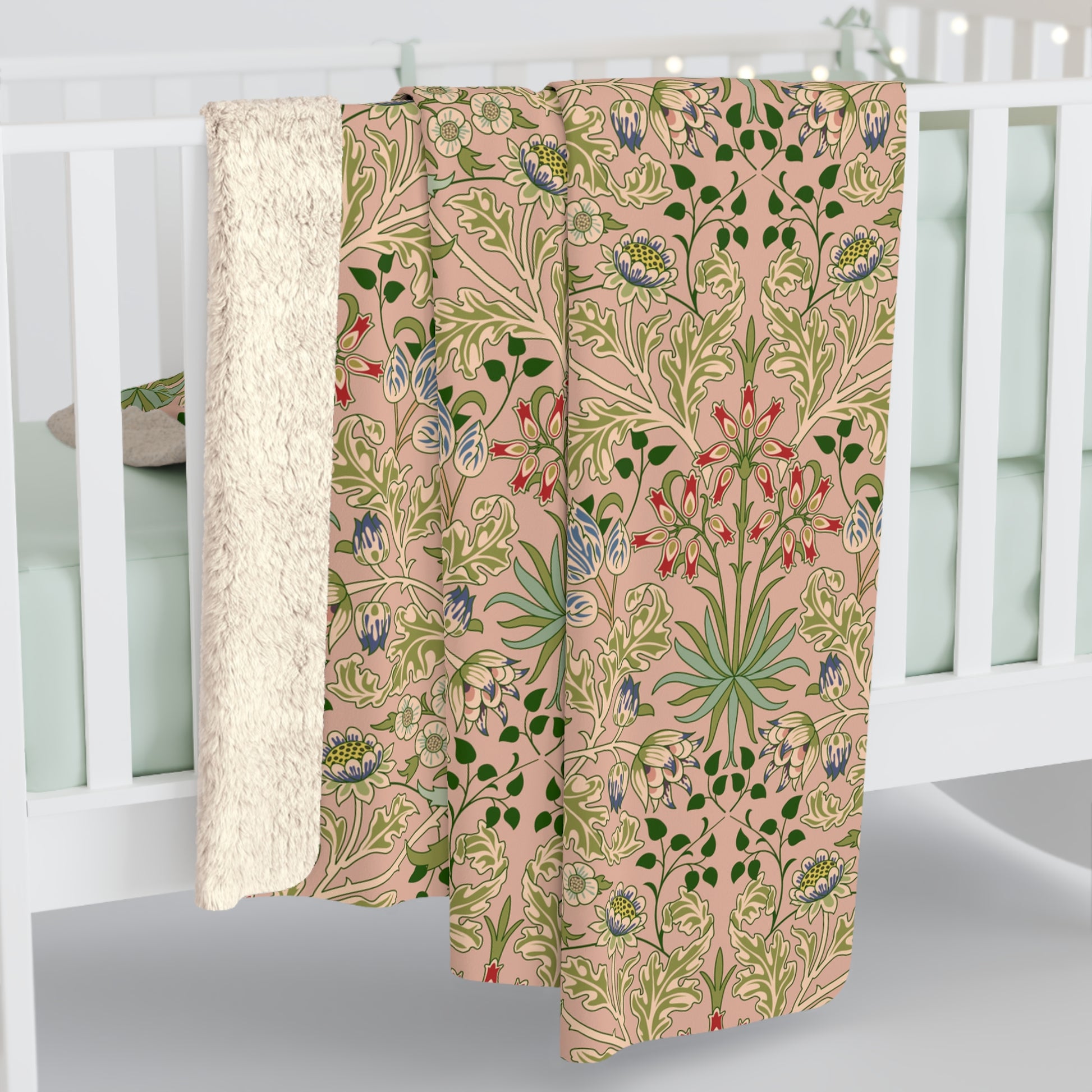 A Sherpa fleece blanket with a floral pattern in pink, green and beige colours on a pink background.