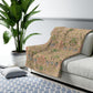A Sherpa fleece blanket with a floral pattern in pink, green and beige colours on a pink background.