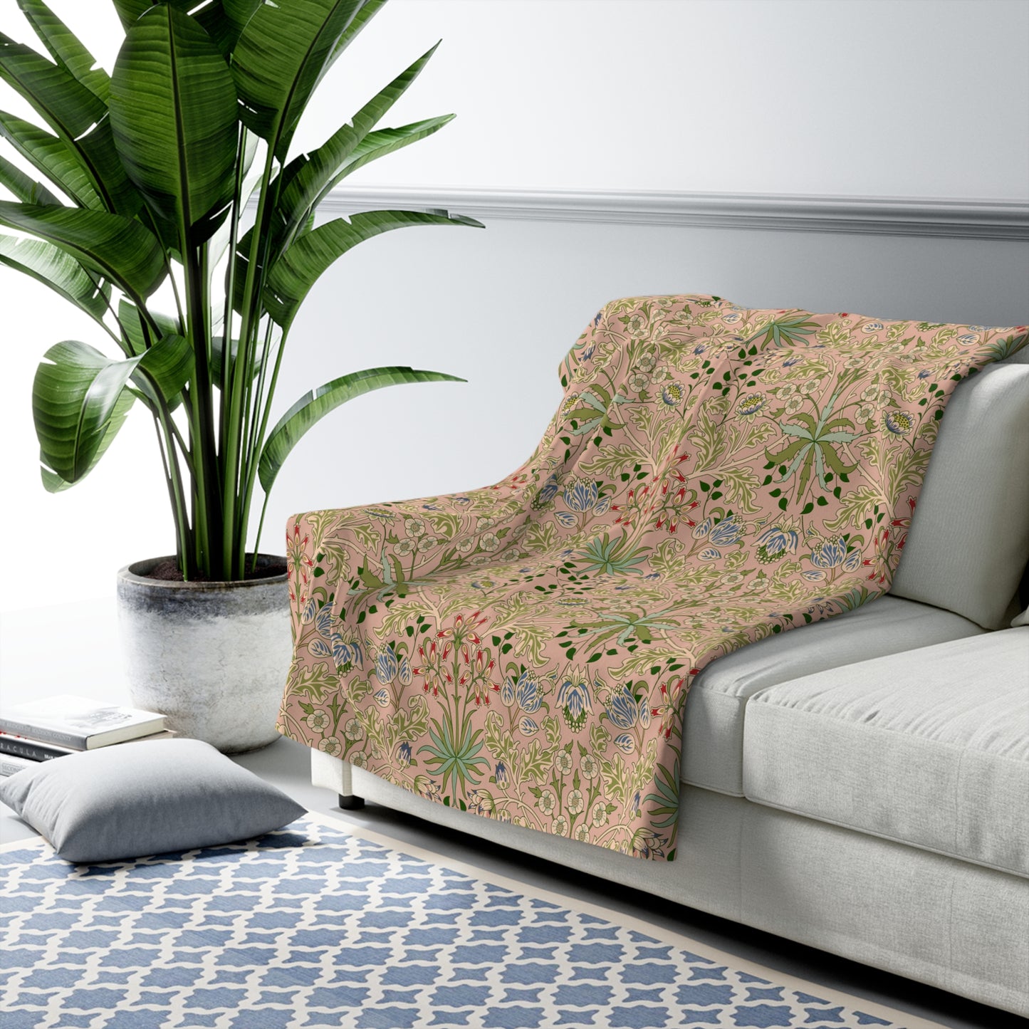 A Sherpa fleece blanket with a floral pattern in pink, green and beige colours on a pink background.