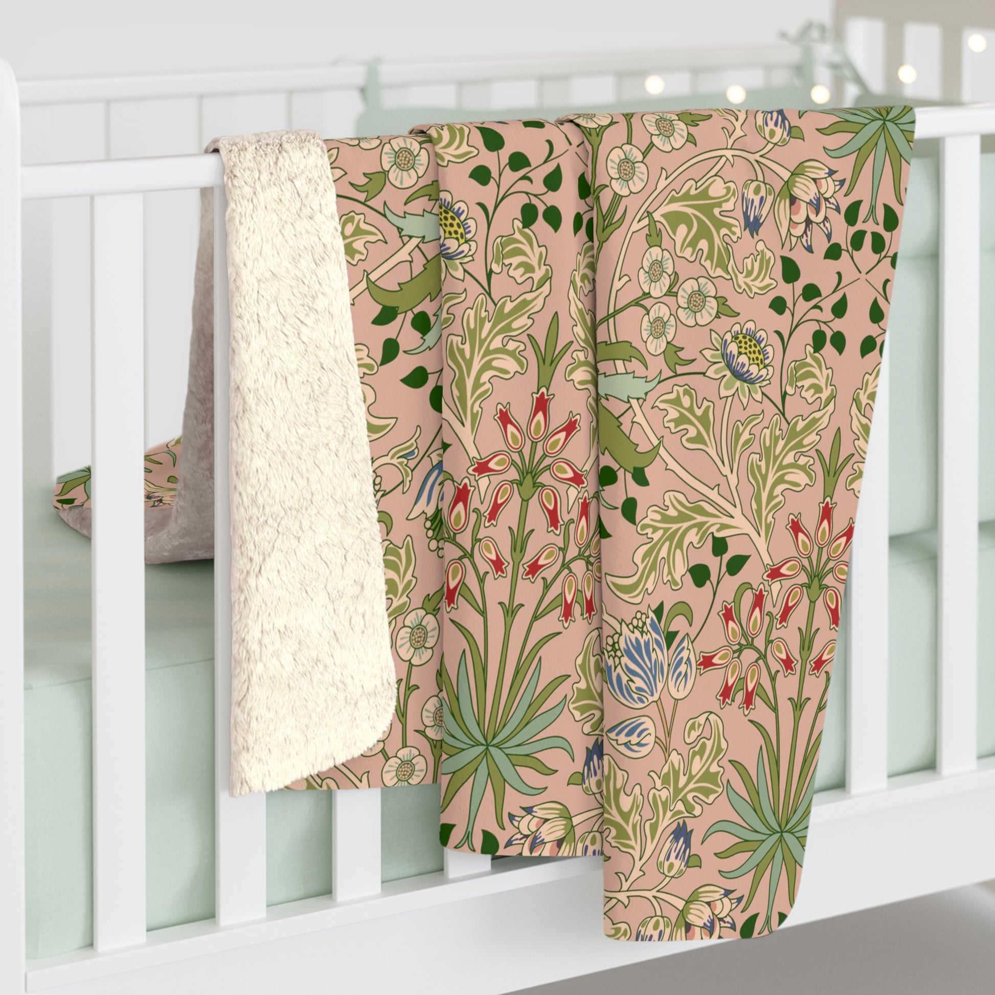 A Sherpa fleece blanket with a floral pattern in pink, green and beige colours on a pink background.