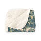 A Sherpa fleece blanket with an all-over floral William Morris & Co pattern in various colours, predominantly teal and cream.