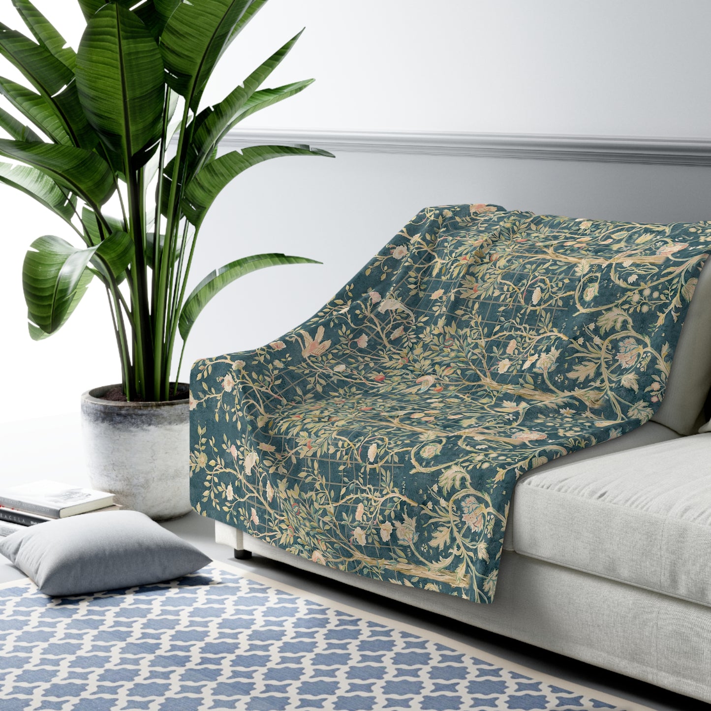 A Sherpa fleece blanket with an all-over floral William Morris & Co pattern in various colours, predominantly teal and cream.