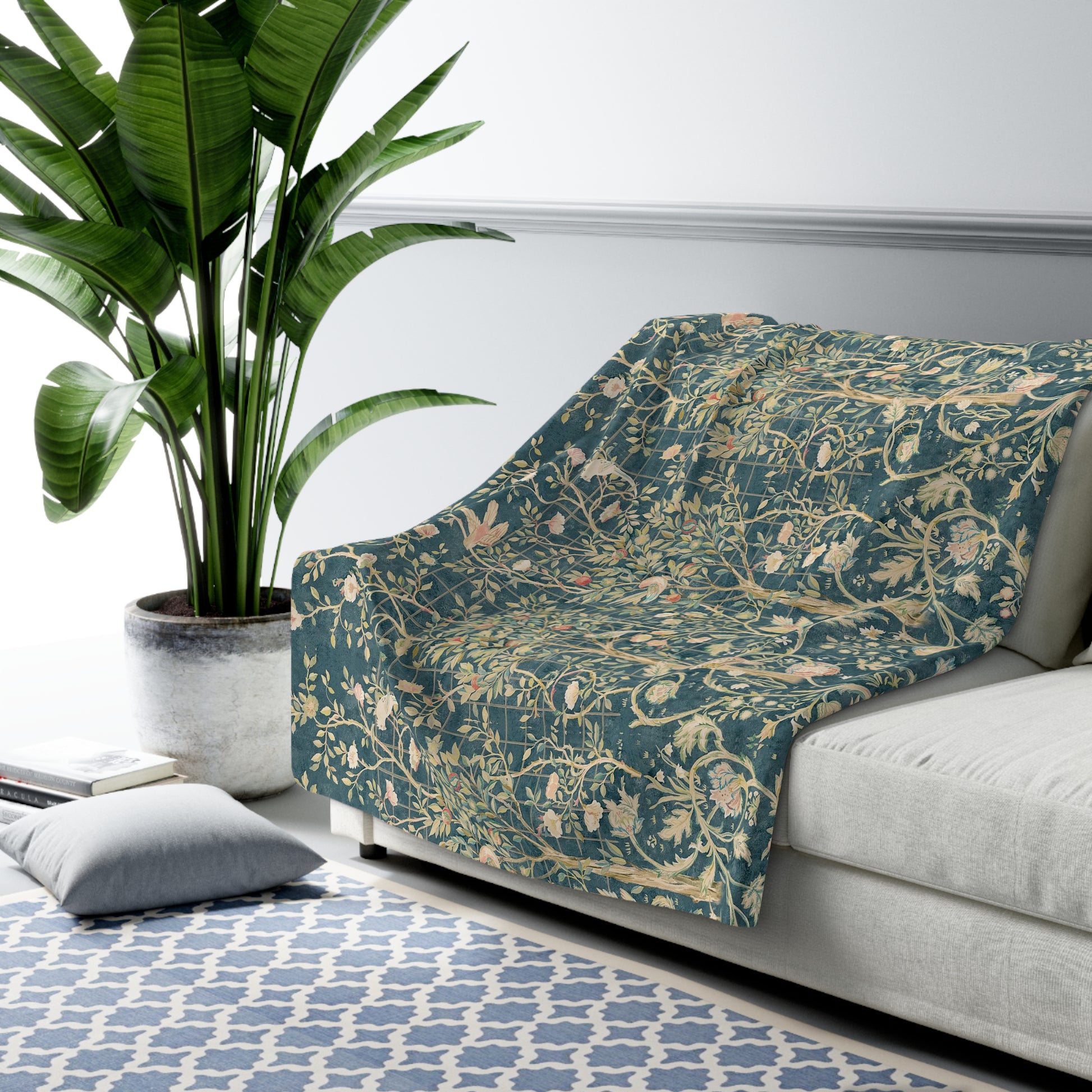 A Sherpa fleece blanket with an all-over floral William Morris & Co pattern in various colours, predominantly teal and cream.