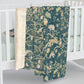A Sherpa fleece blanket with an all-over floral William Morris & Co pattern in various colours, predominantly teal and cream.