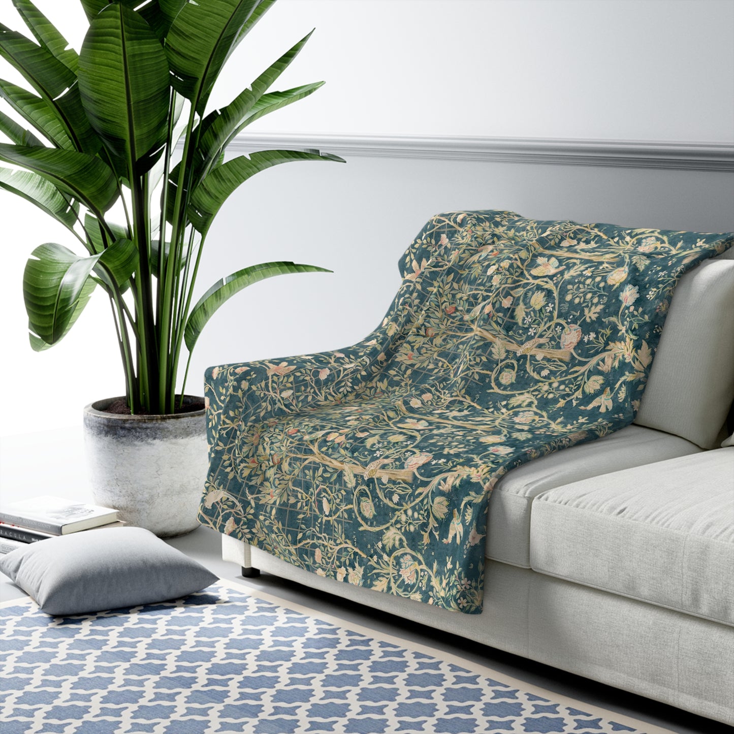A Sherpa fleece blanket with an all-over floral William Morris & Co pattern in various colours, predominantly teal and cream.
