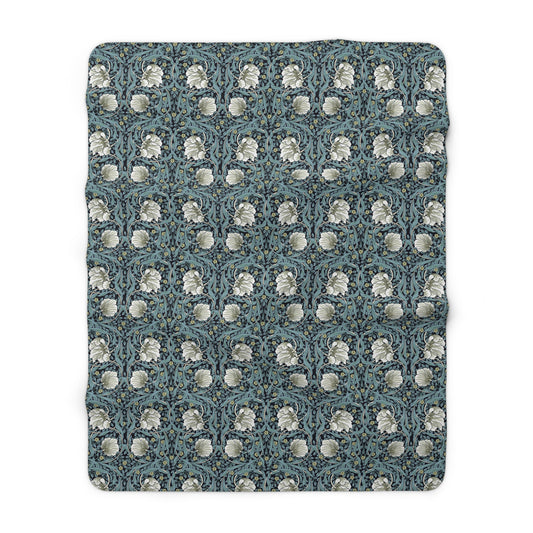 A plush fleece blanket with a geometric William Morris & Co pattern in a slate blue colour, featuring a dense, cozy texture.