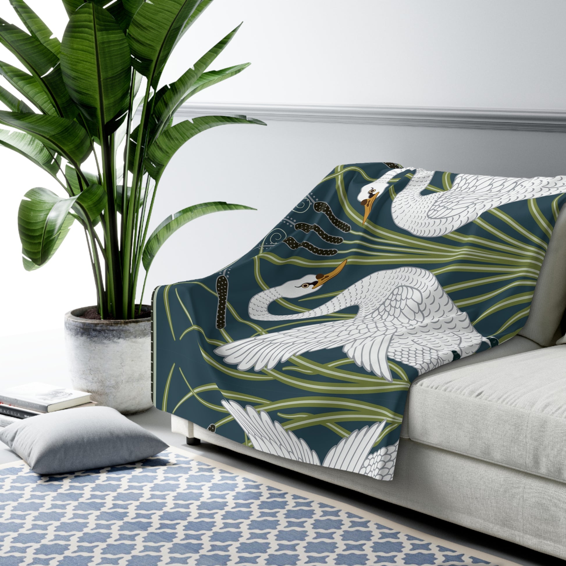 A Sherpa fleece blanket with a floral and swan William Morris & Co pattern in white and green colours on a dark background.