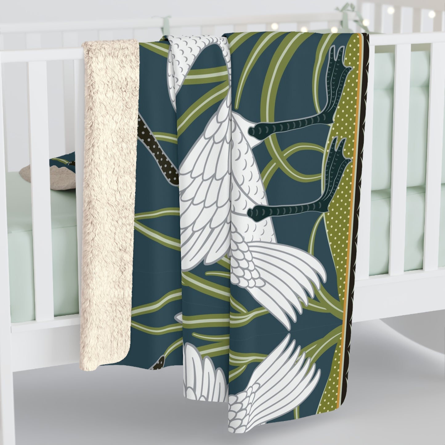 A Sherpa fleece blanket with a floral and swan William Morris & Co pattern in white and green colours on a dark background.