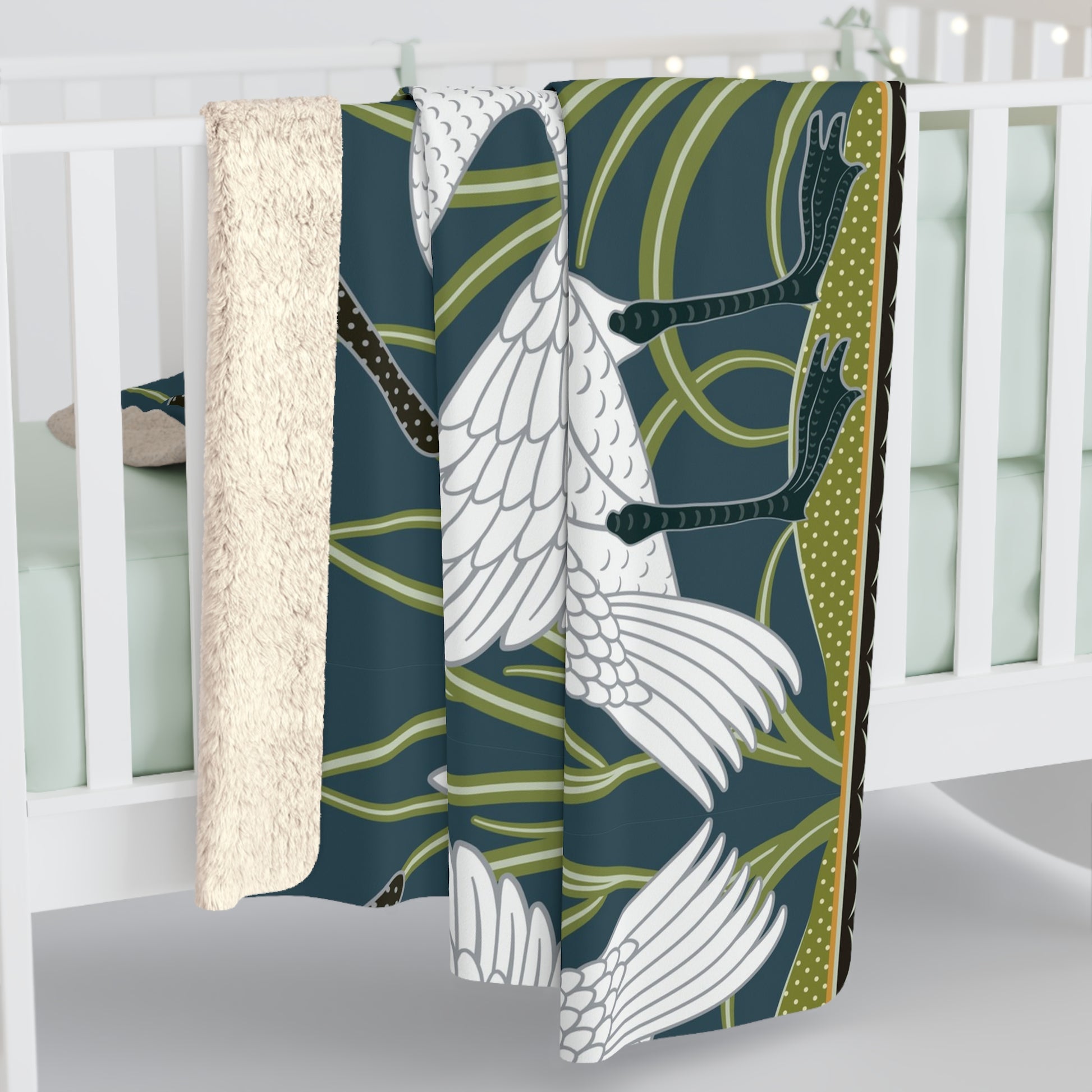 A Sherpa fleece blanket with a floral and swan William Morris & Co pattern in white and green colours on a dark background.