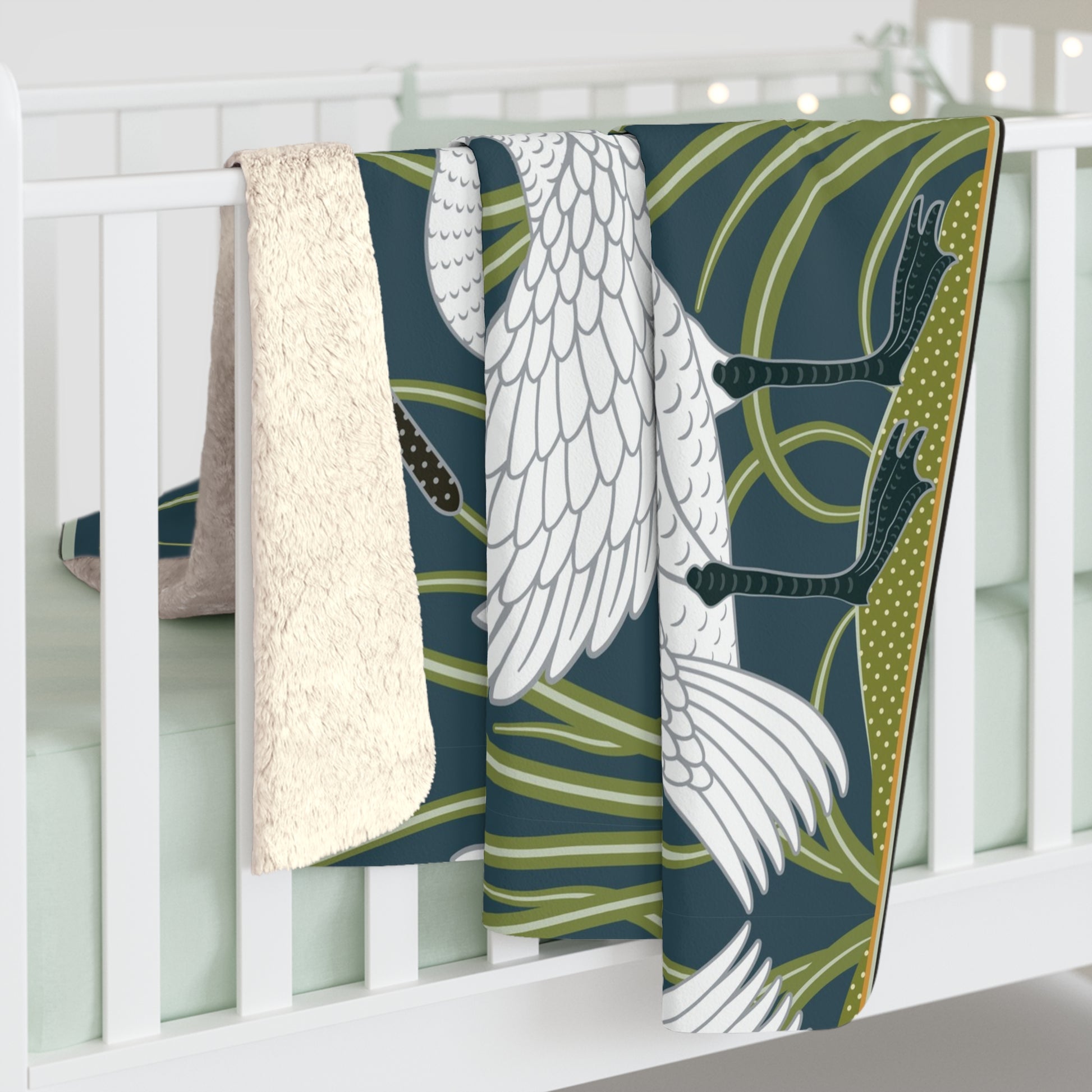 A Sherpa fleece blanket with a floral and swan William Morris & Co pattern in white and green colours on a dark background.