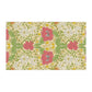 A kitchen tea towel with a floral pattern inspired by William Morris, featuring honeysuckle designs in red, yellow, and green on a light background.
