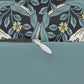 A rectangular lumbar cushion with a William Morris & Co floral pattern in shades of blue, beige, and white, featuring a concealed beige zipper.