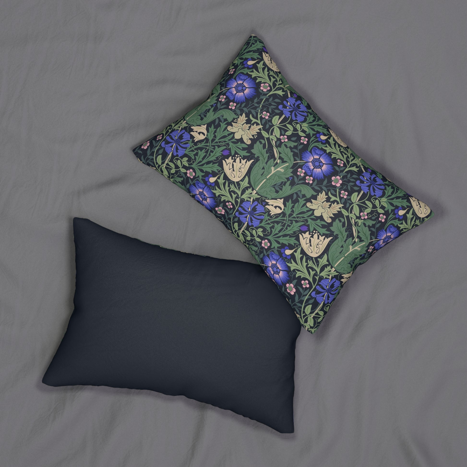 A rectangular lumbar cushion with a floral William Morris & Co pattern featuring predominantly blue flowers and green leaves on a darker background.