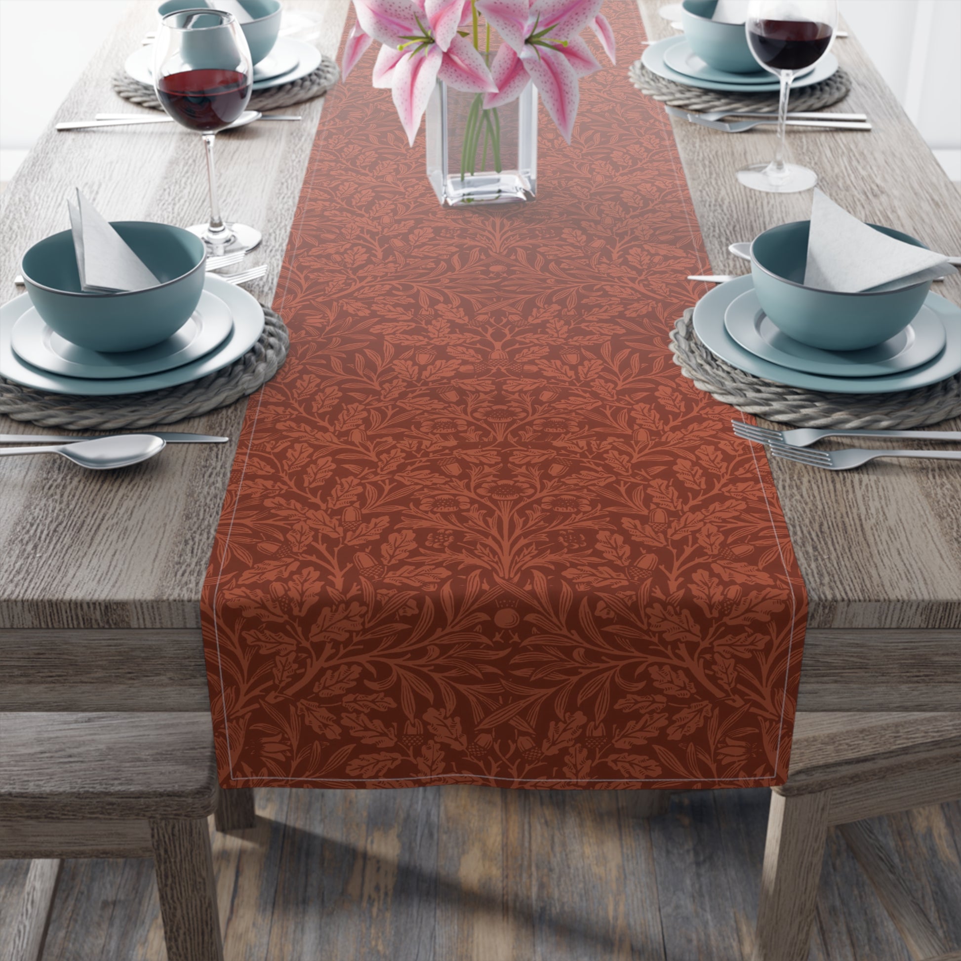 A rust-coloured table runner with a floral William Morris & Co pattern displayed on a dining table.