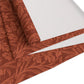 A rust-coloured table runner with a floral William Morris & Co pattern displayed on a dining table.
