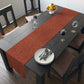 A rust-coloured table runner with a floral William Morris & Co pattern displayed on a dining table.