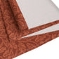 A rust-coloured table runner with a floral William Morris & Co pattern displayed on a dining table.
