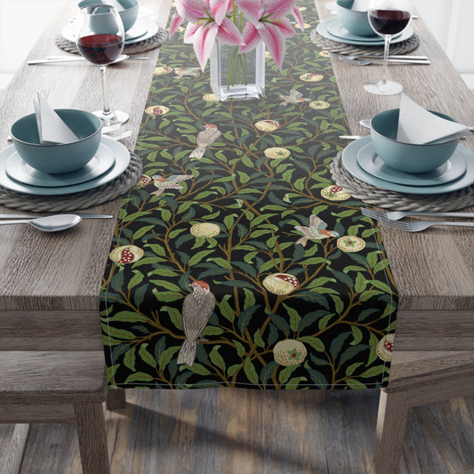A table runner with a Victorian-inspired bird and pomegranate William Morris & Co pattern in black, green, and white, displayed on a dining table.