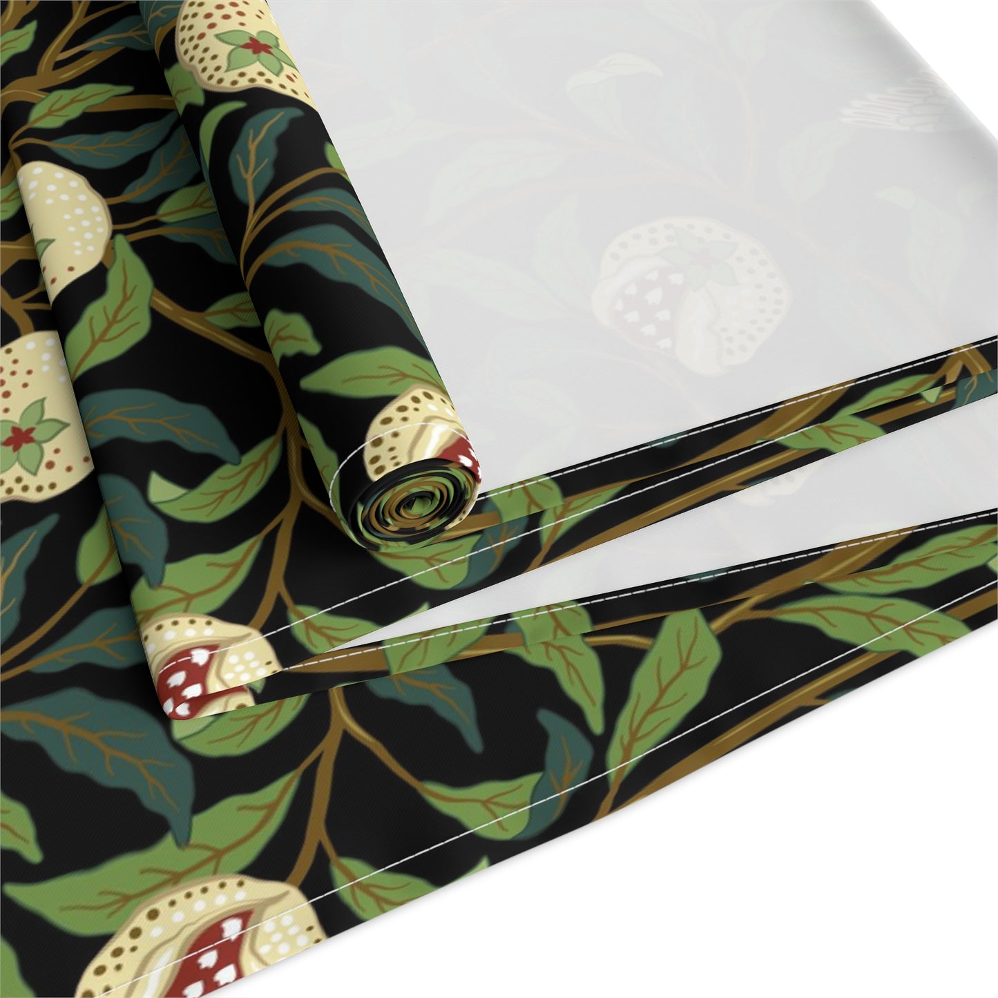 A table runner with a Victorian-inspired bird and pomegranate William Morris & Co pattern in black, green, and white, displayed on a dining table.