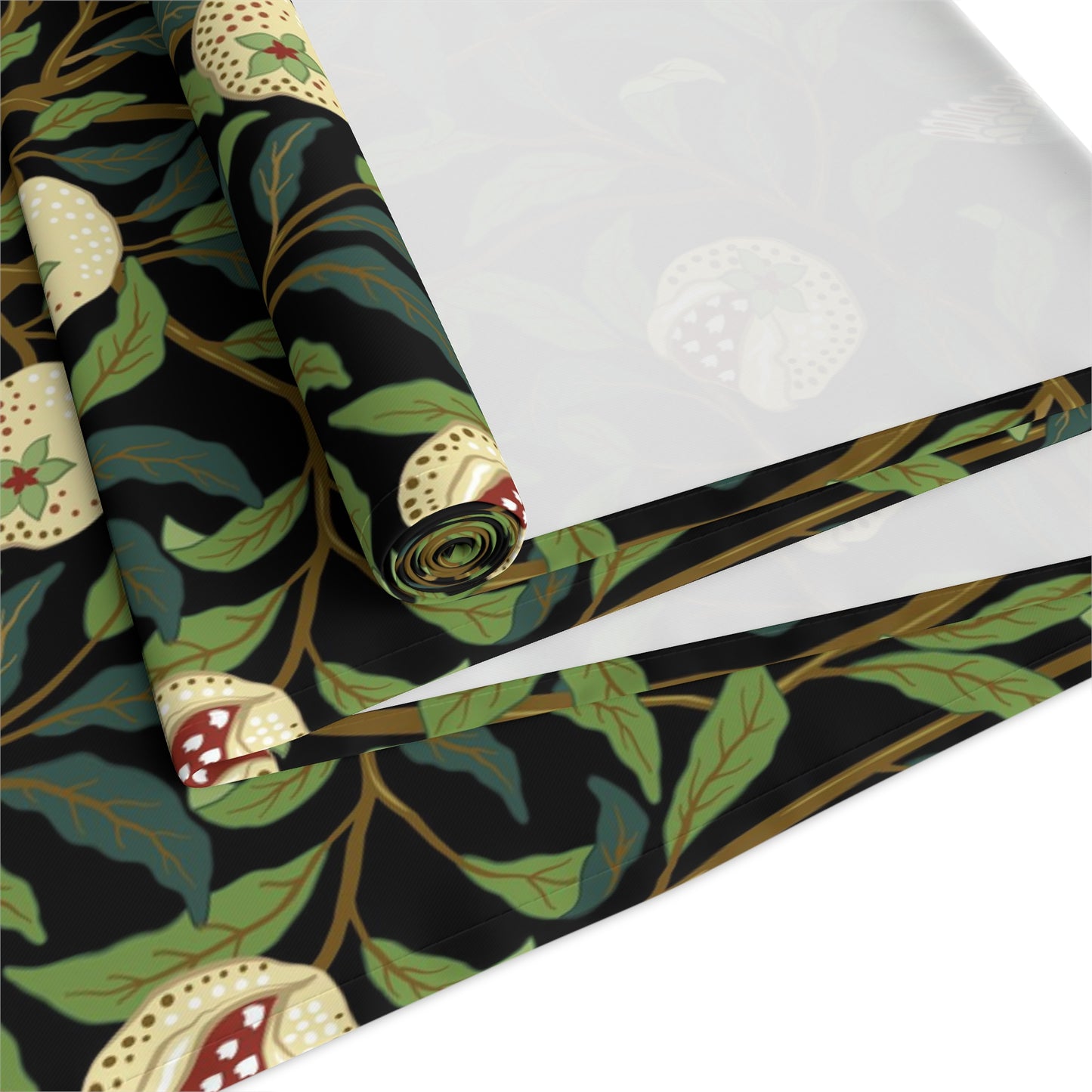 A table runner with a Victorian-inspired bird and pomegranate William Morris & Co pattern in black, green, and white, displayed on a dining table.