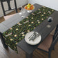 A table runner with a Victorian-inspired bird and pomegranate William Morris & Co pattern in black, green, and white, displayed on a dining table.