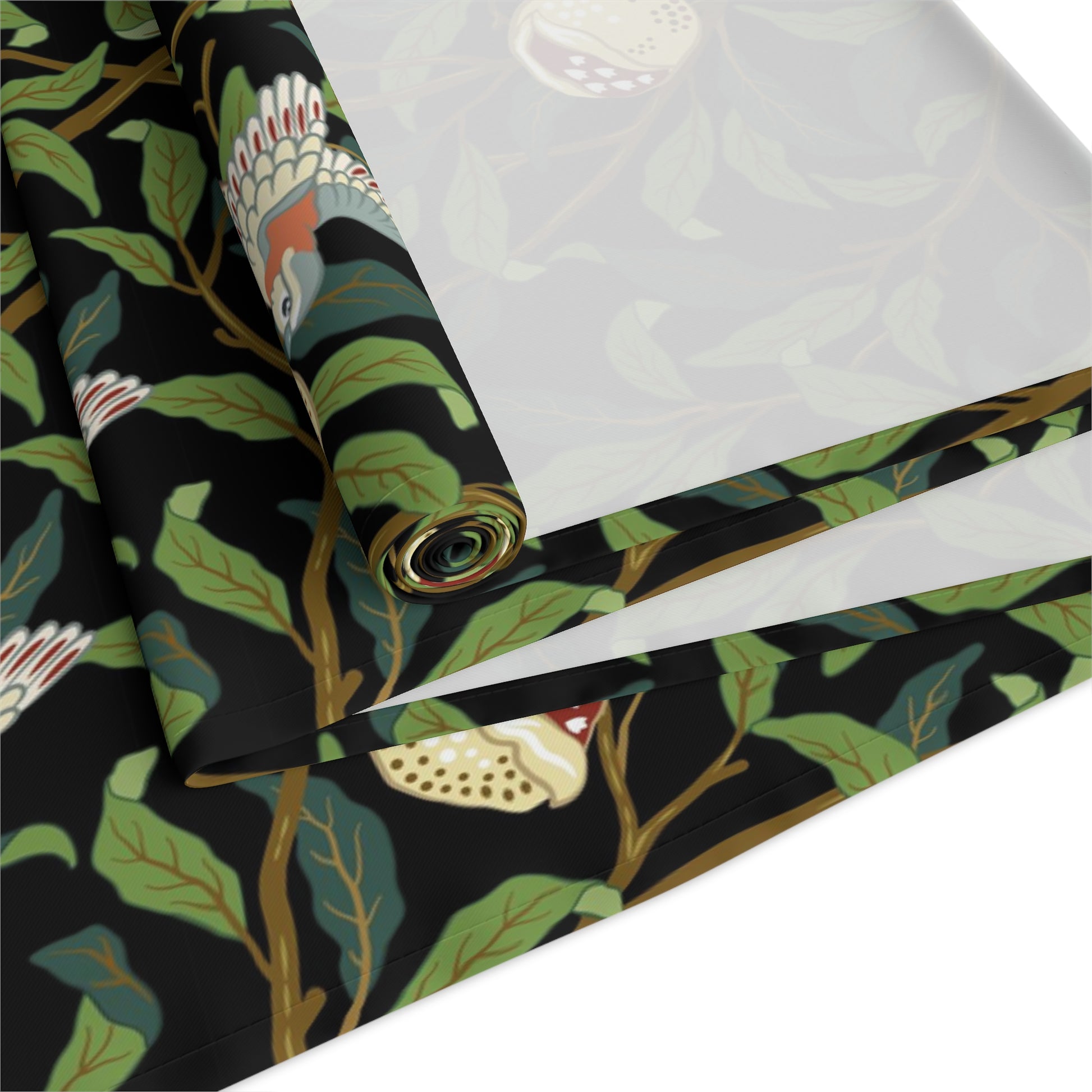 A table runner with a Victorian-inspired bird and pomegranate William Morris & Co pattern in black, green, and white, displayed on a dining table.
