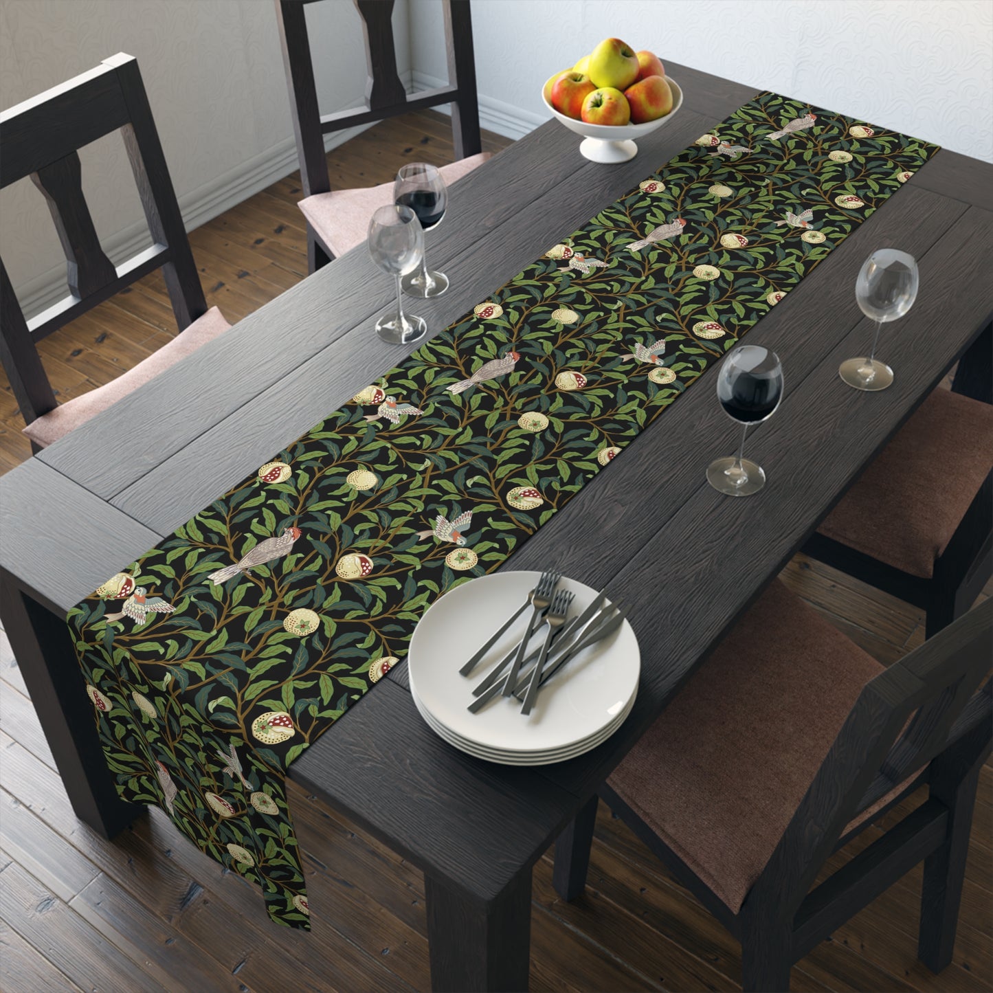A table runner with a Victorian-inspired bird and pomegranate William Morris & Co pattern in black, green, and white, displayed on a dining table.