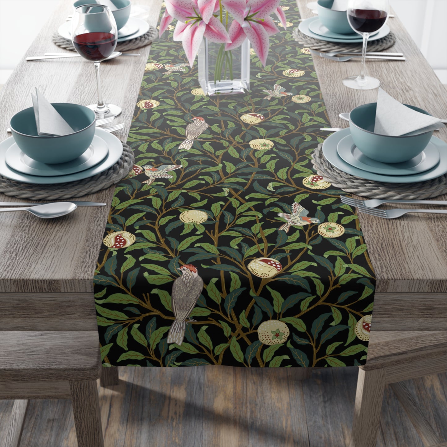 A table runner with a Victorian-inspired bird and pomegranate pattern in black, green, and white, displayed on a dining table.