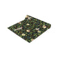 A table runner with a Victorian-inspired bird and pomegranate William Morris & Co pattern in black, green, and white, displayed on a dining table.