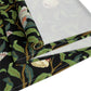 A table runner with a Victorian-inspired bird and pomegranate William Morris & Co pattern in black, green, and white, displayed on a dining table.