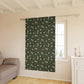 Window with a green patterned curtain in a room with a sofa and window sill.